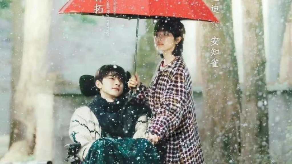 Lin Yi sits on a wheelchair while Landy Li holds an umbrella over his head