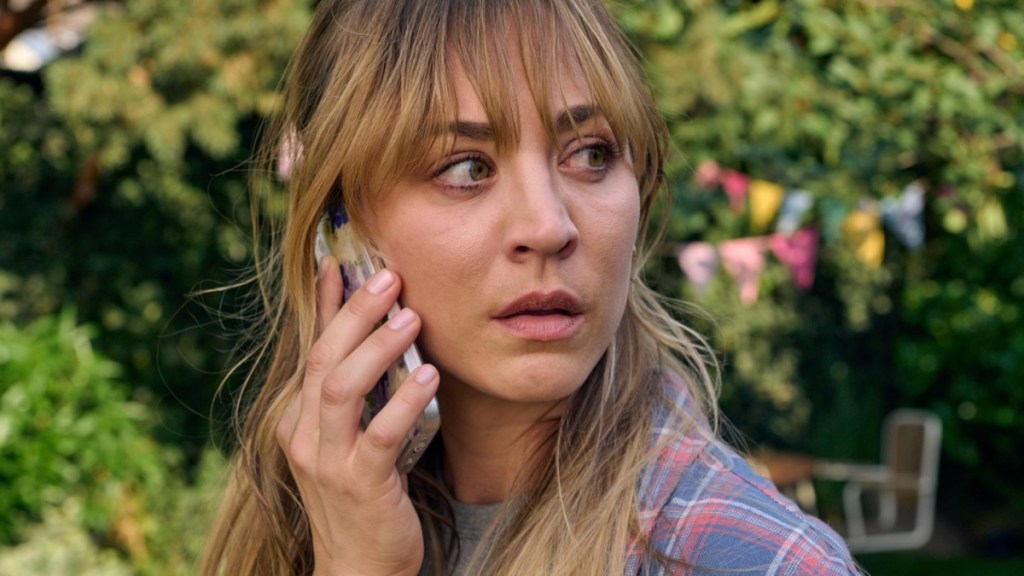 Kaley Cuoco stares while holding a phone to her ear.