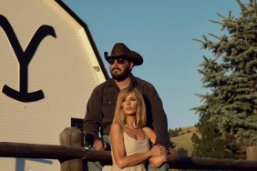 A woman stands in front of a man sitting on a fence in Yellowstone.