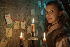 A girl holds up a candle to a board.