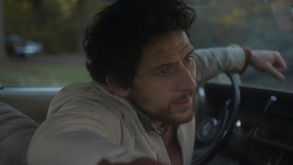 Josh O'Connor sits in front seat of car in The Mastermind.