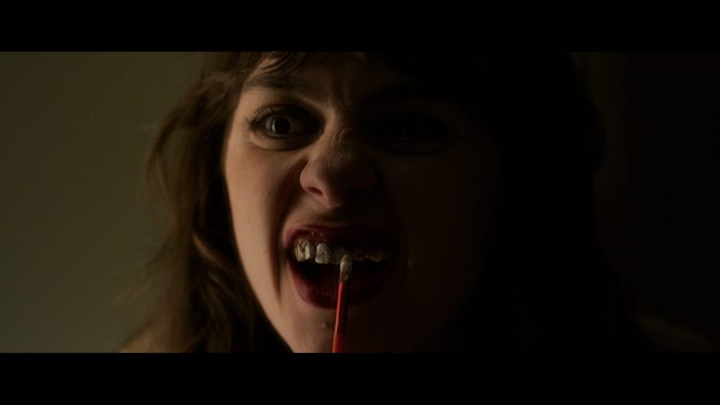 A woman fixes her tooth in Morgan: Killer Doll.