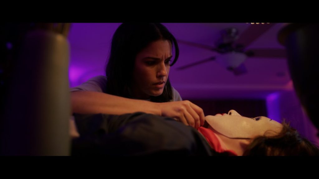 A woman puts her hand up to doll in Morgan: Killer Doll.